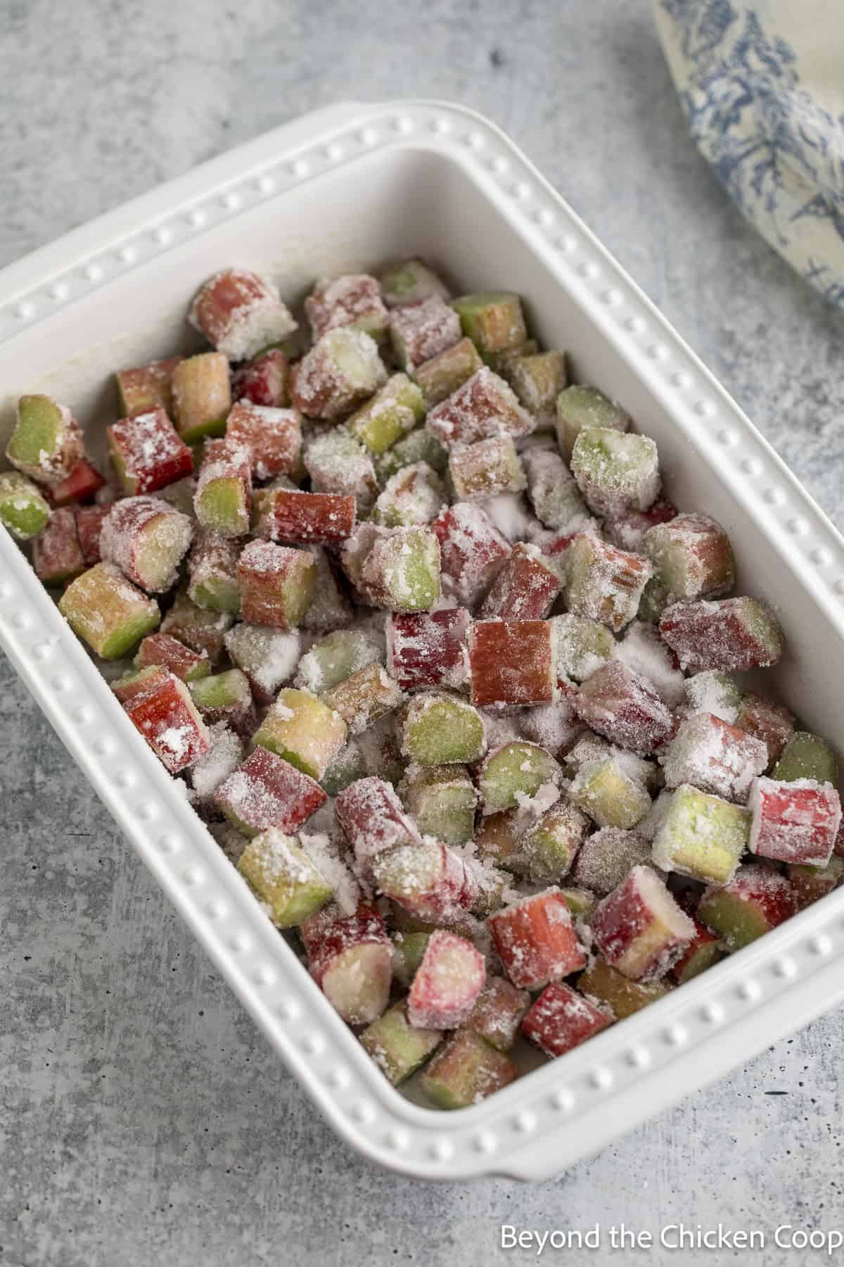 Rhubarb with sugar in a white baking dish.