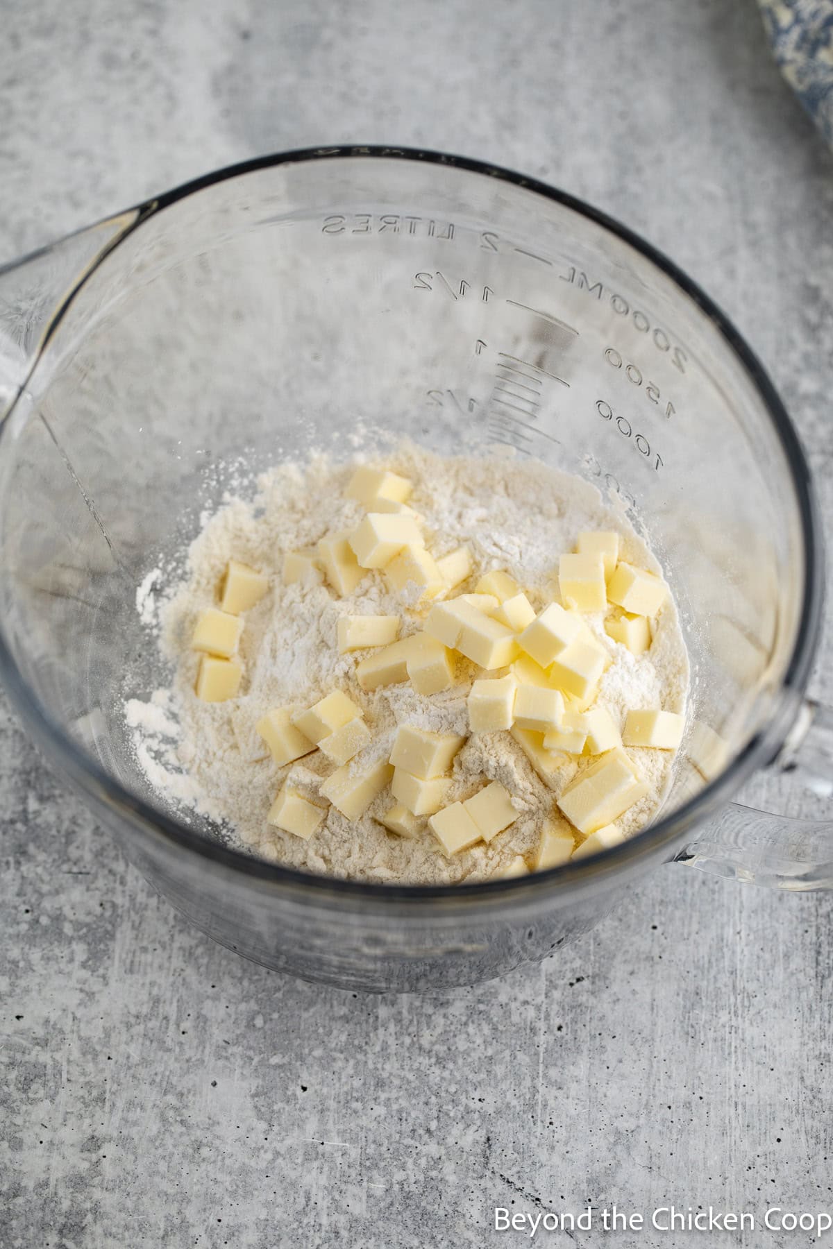A glass bowl with flour and small cubes of butter.