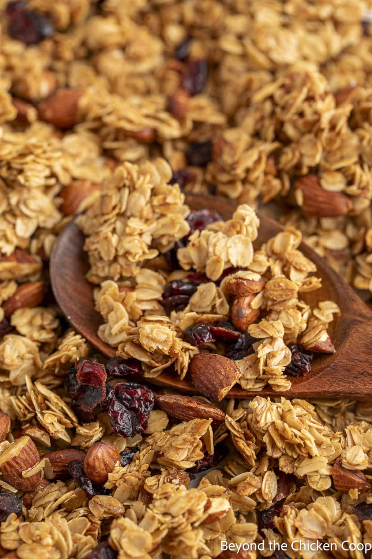 Baked granola on a baking sheet with a wooden spoon.