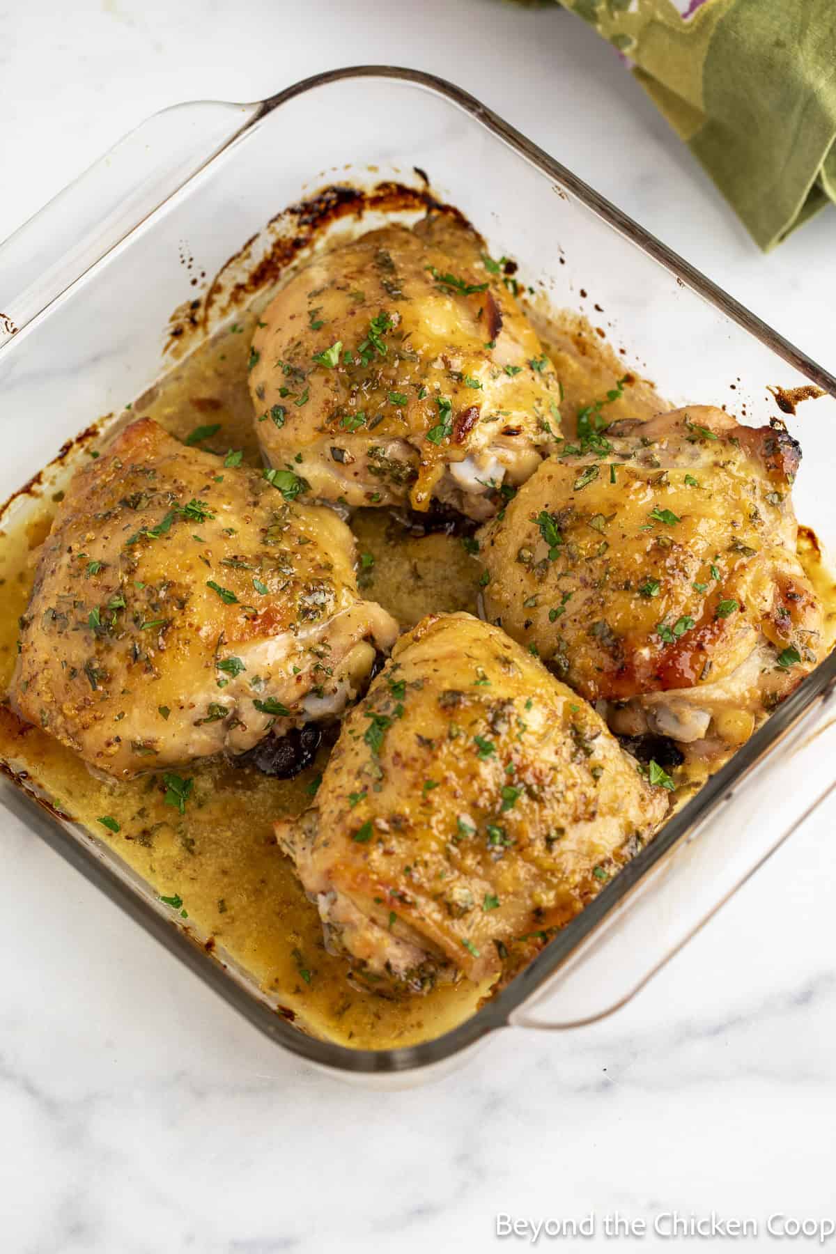 Baked chicken thighs topped with herbs in a baking dish.