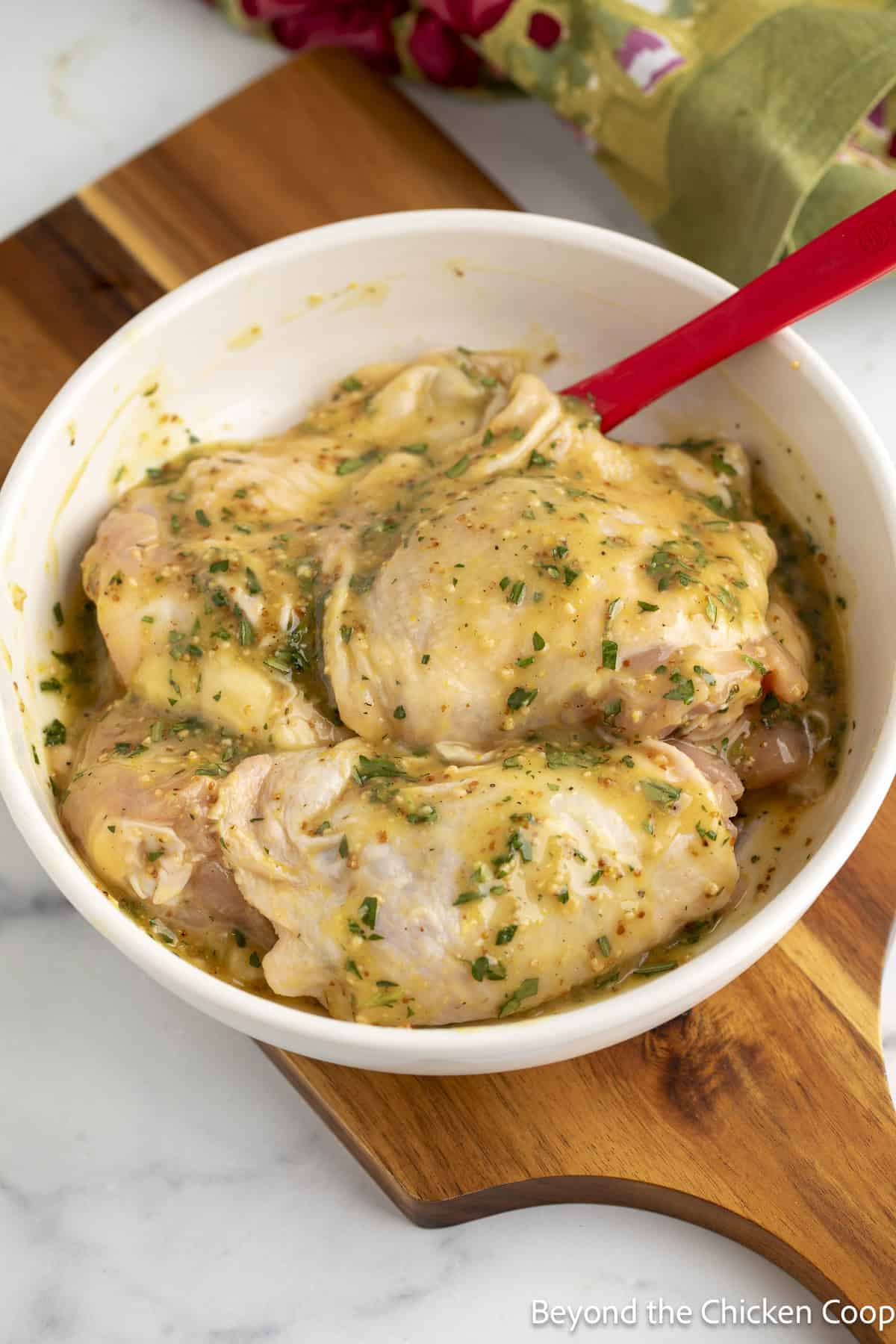 Raw chicken thighs covered with marinade in a bowl.