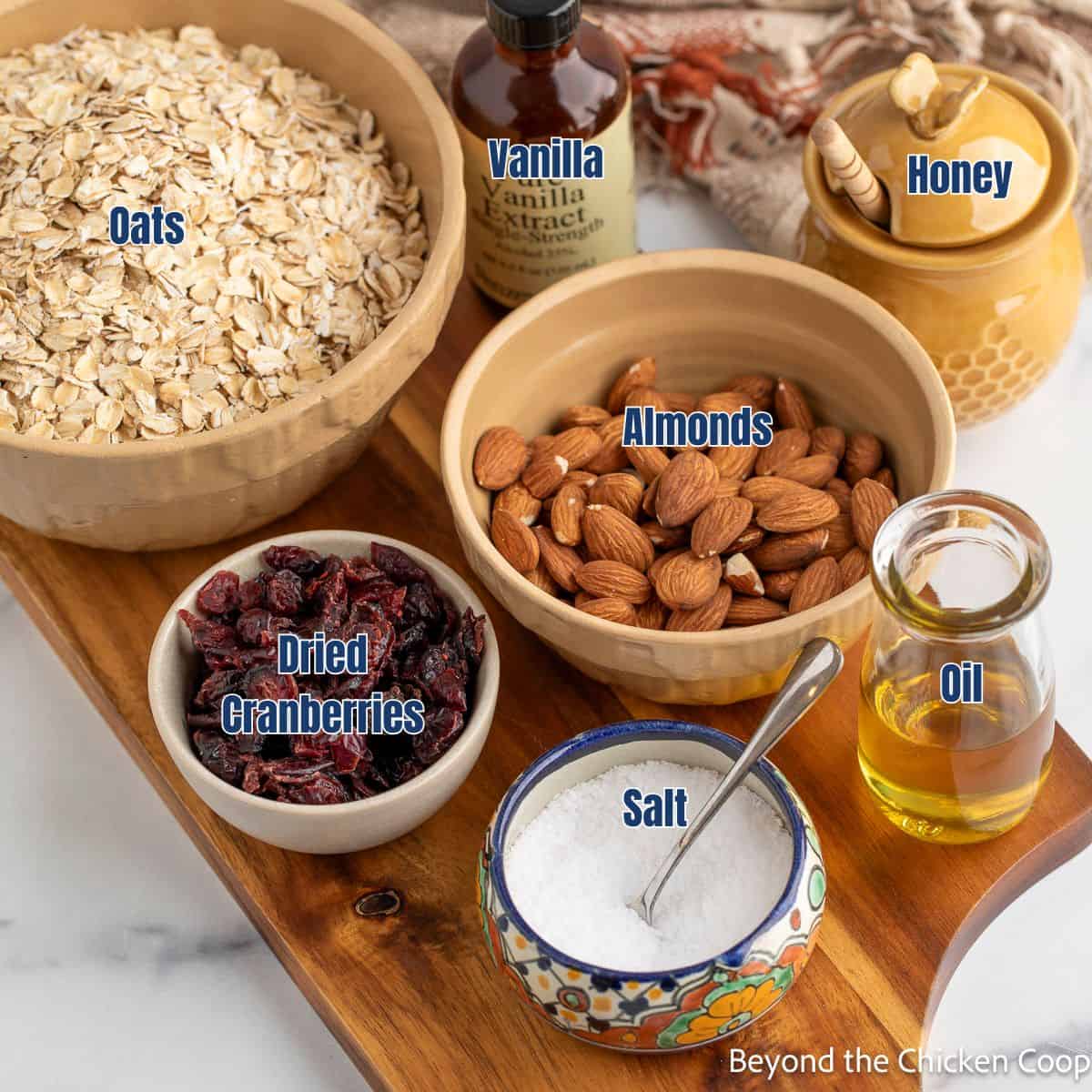 Bowls filled with dried oats, almonds, cranberries, and other ingredients.