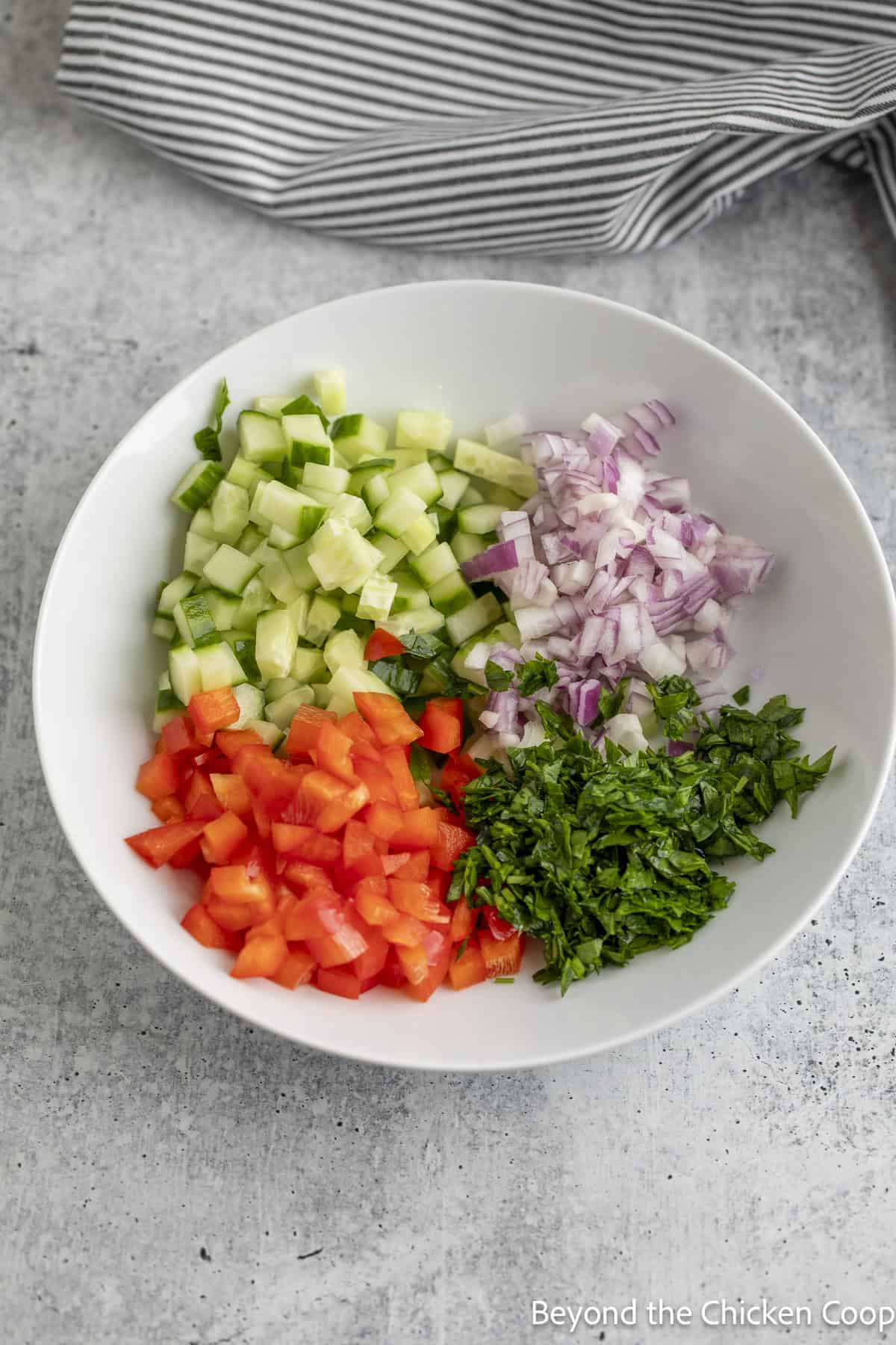 Diced veggies and herbs in a white bowl.