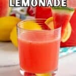 A glass filled with pink lemonade with a watermelon wedge on the rim of the glass.