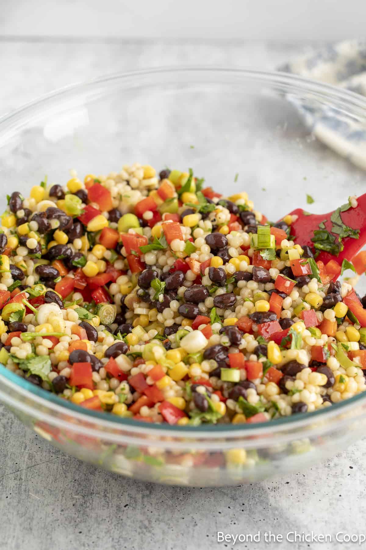 Mixing a pasta salad together in a large glass bowl.