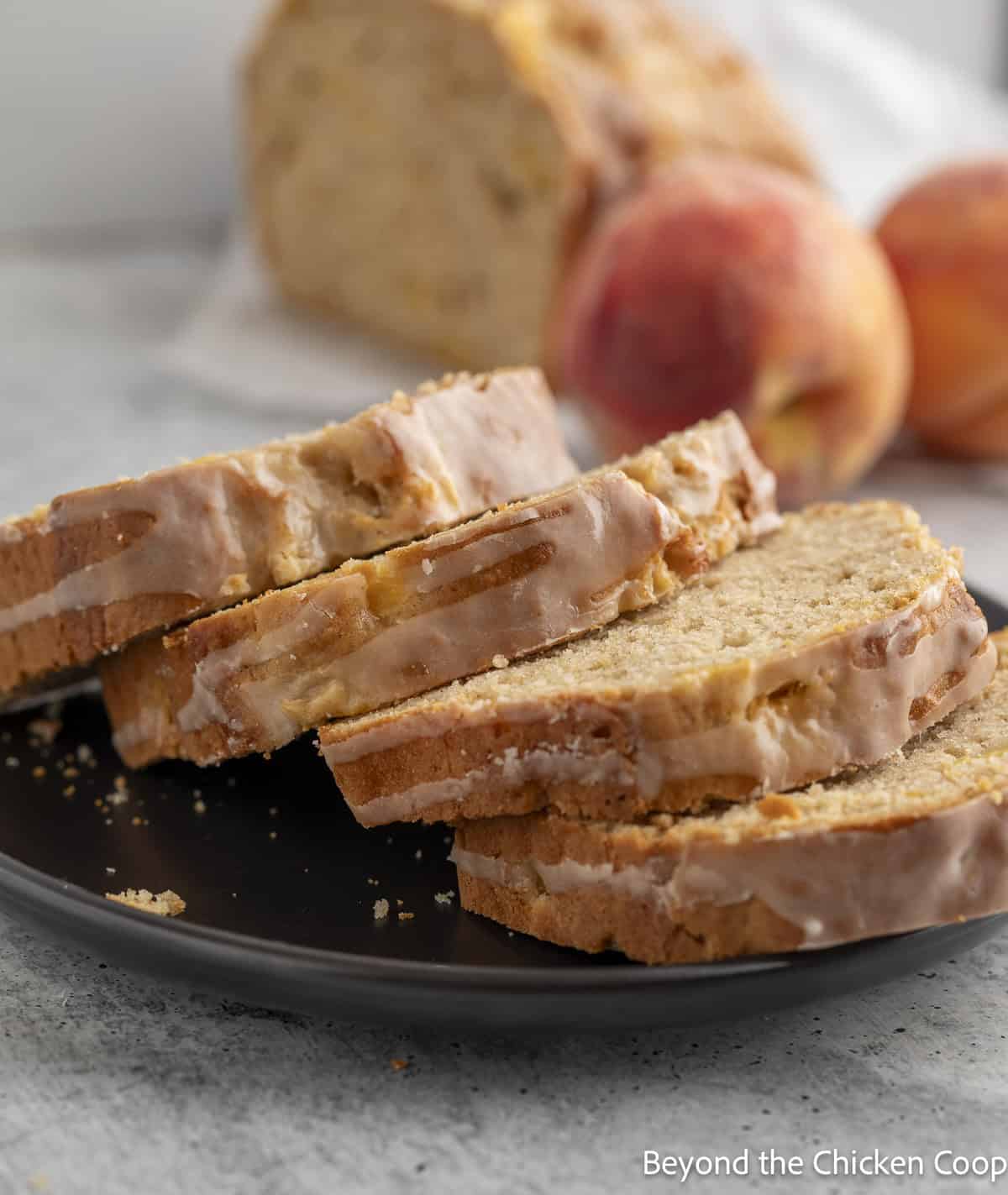 Sliced peach quick bread on a black plate.