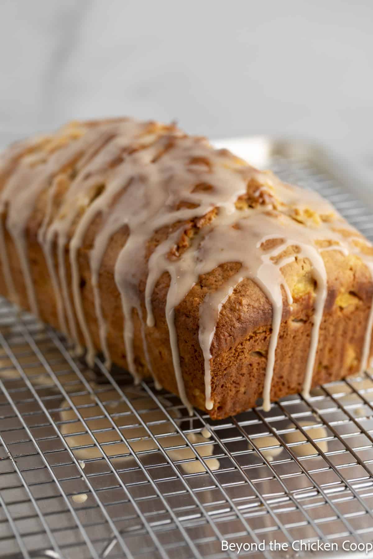 A loaf of peach bread with glaze dripping over the top of the loaf.
