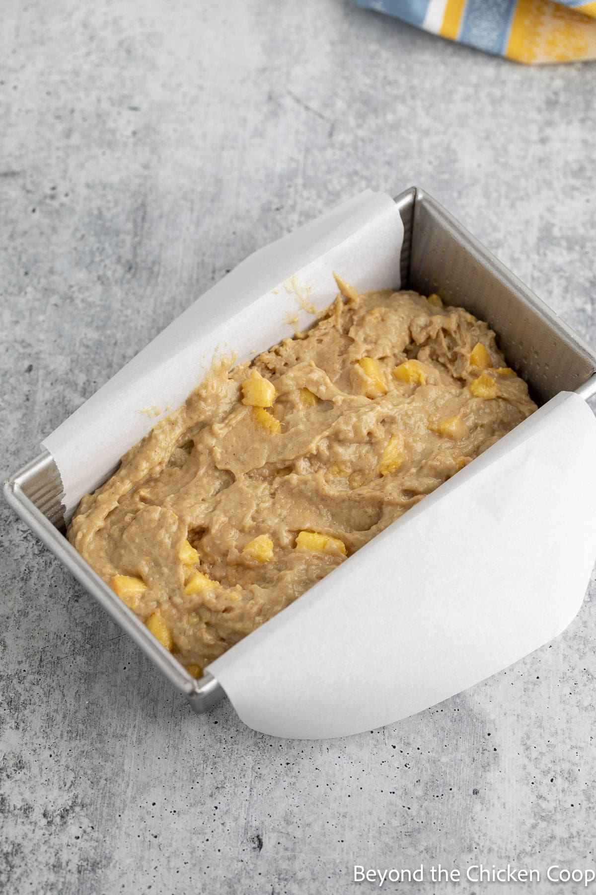 A bread pan filled with peach bread batter.