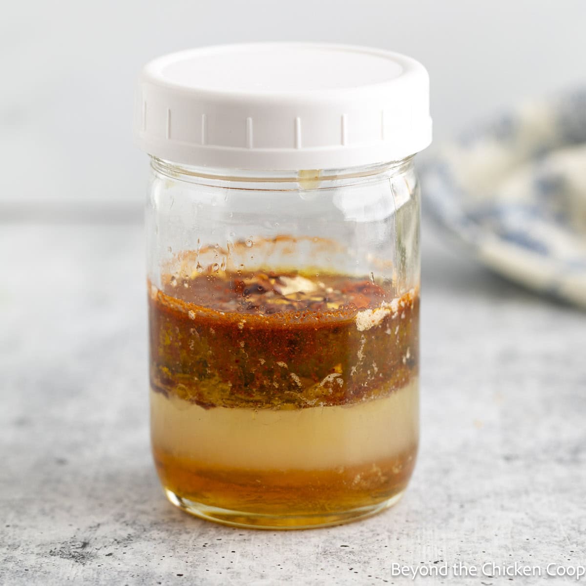 Layered ingredients for a dressing in a glass jar.