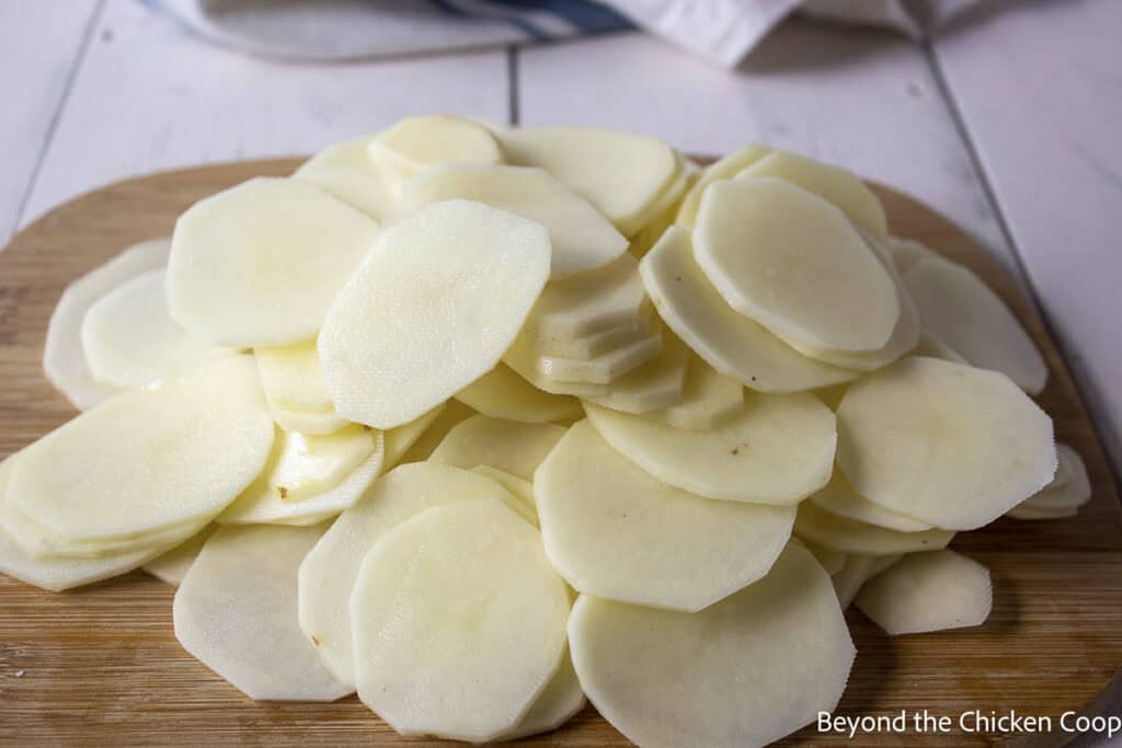 Thinly sliced potatoes on a board.