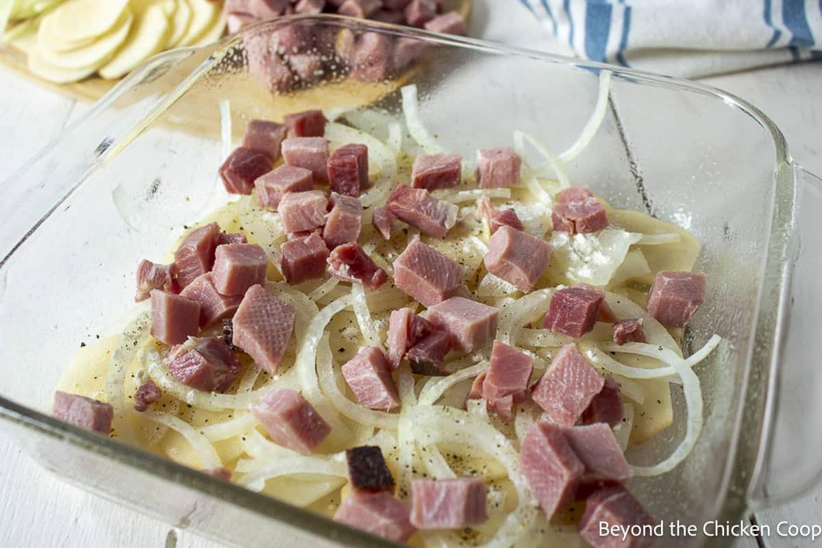 Layering a casserole with potatoes, onions, and ham.