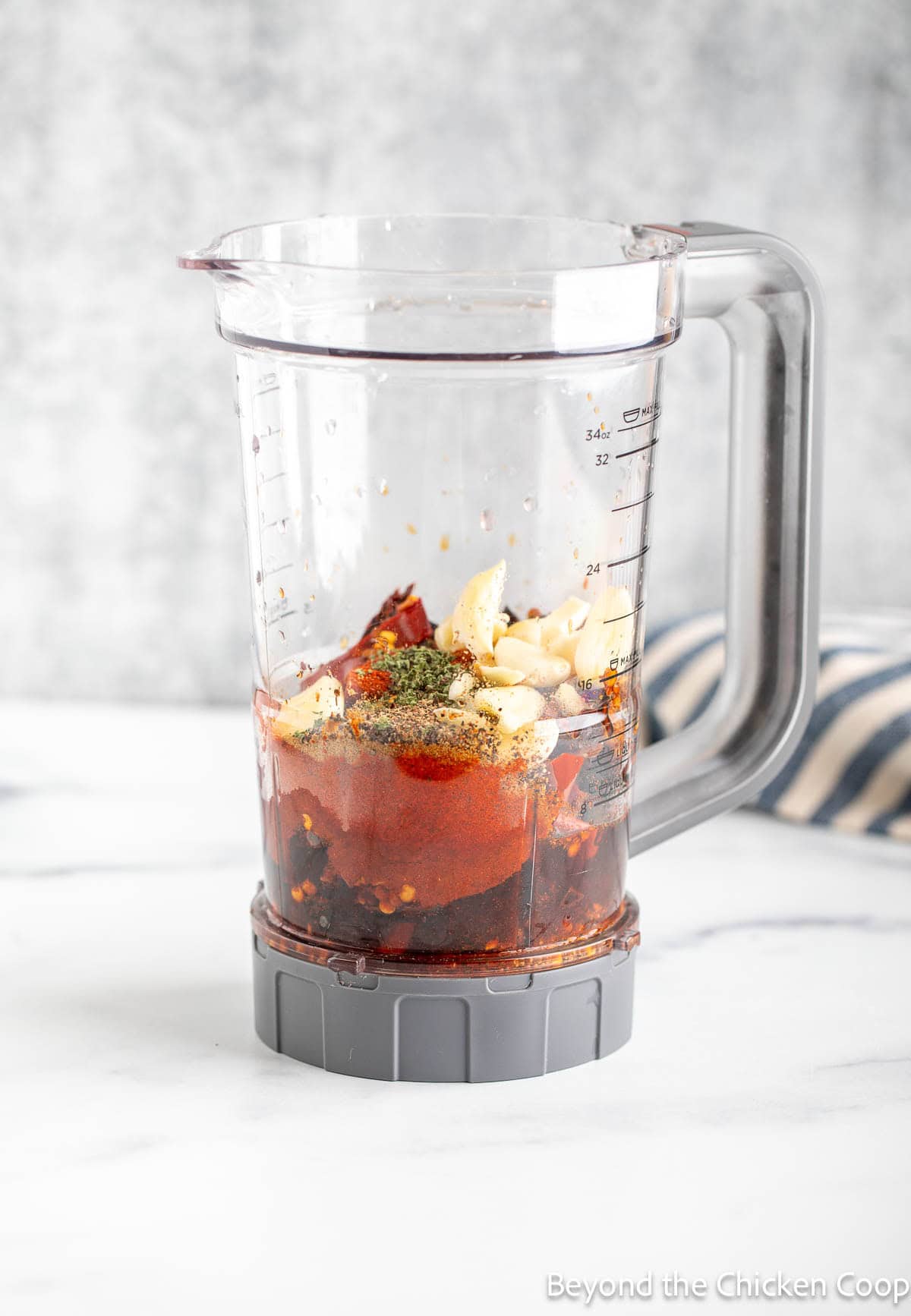 A blender with chiles, seasoning, and garlic.