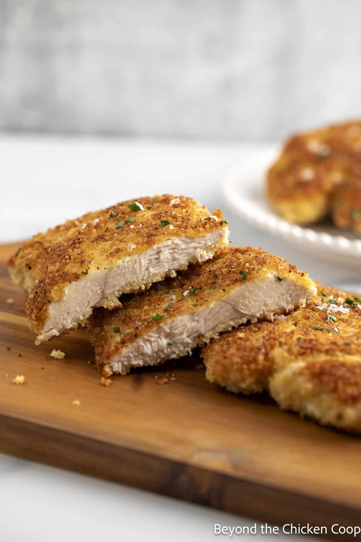 Sliced breaded chicken breasts on a cutting board.