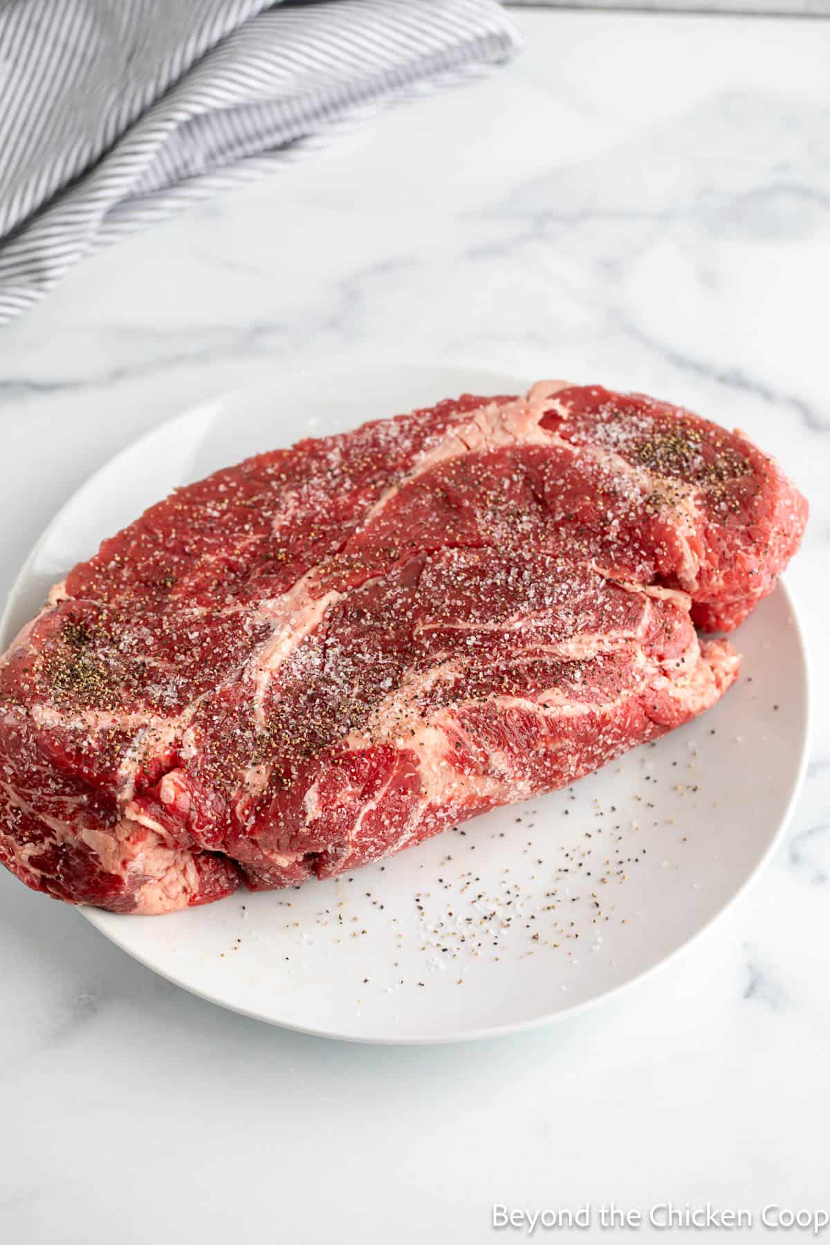 A seasoned chuck roast on a plate.