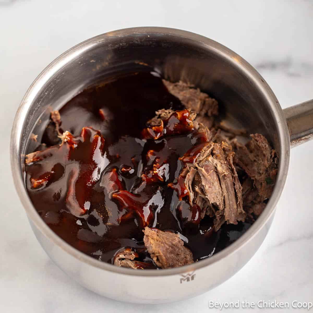 Shredded beef with barbecue sauce in a saucepan.