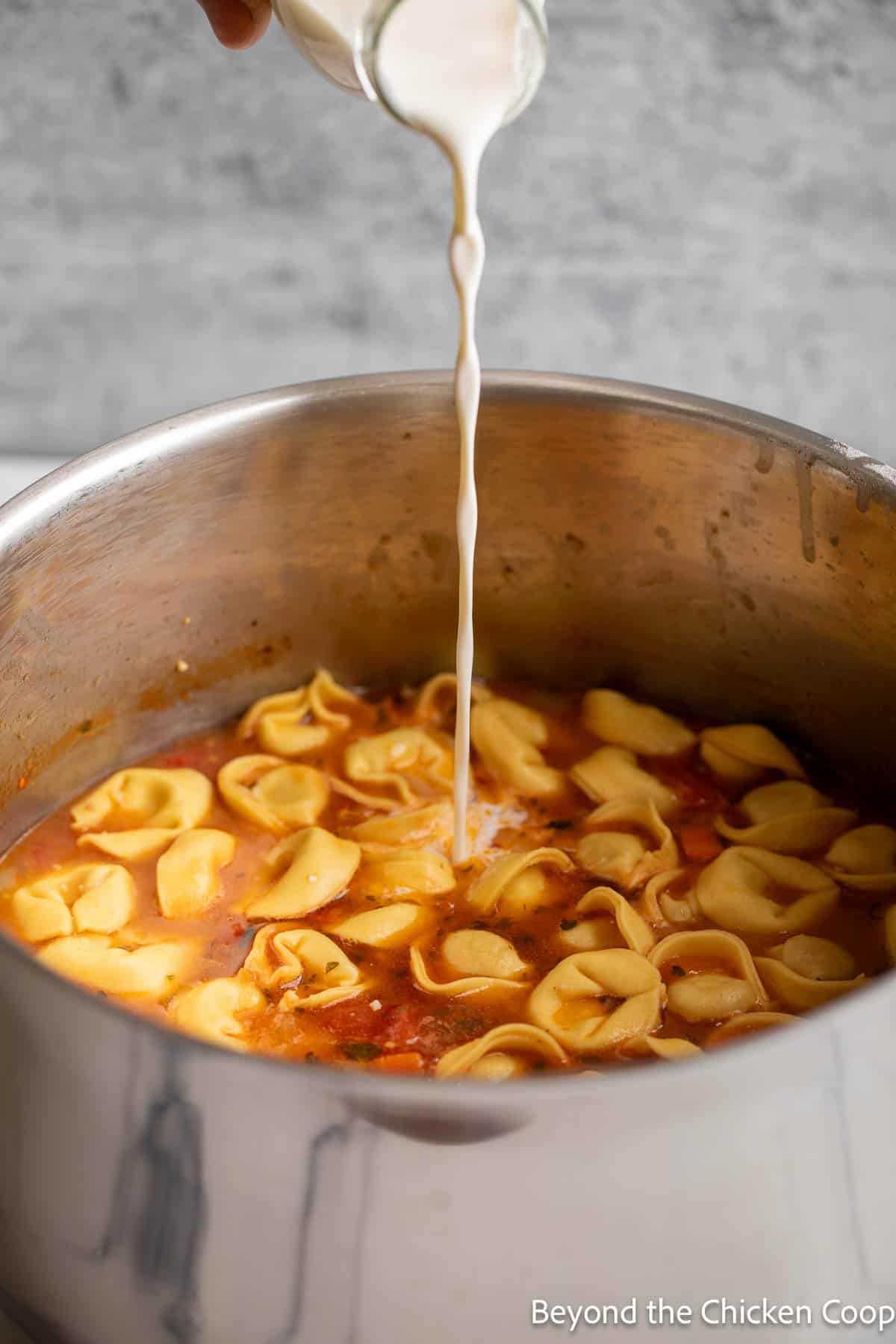 Pouring cream into a pot of soup.