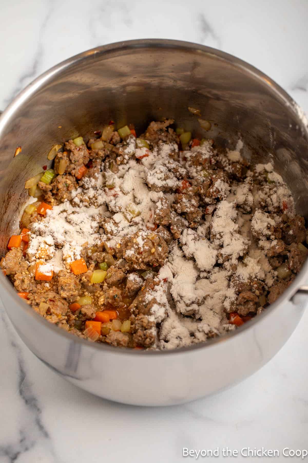 Browned sausage sprinkled with flour in a stockpot.