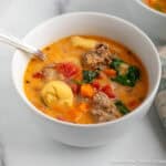 Creamy Tortellini Soup with spinach in a white bowl.